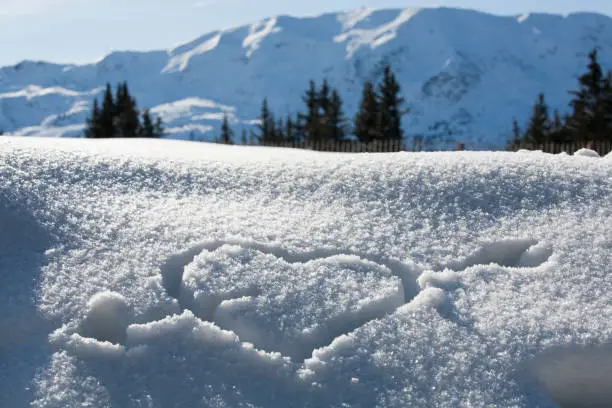 pierced heart drawn in the snow in the sun