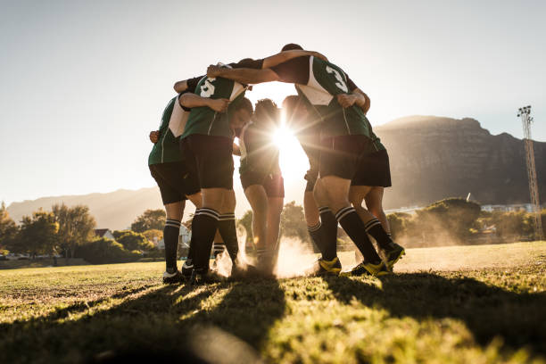 Rugby players rejoicing victory Rugby team standing in a huddle and rubbing their feet on ground. Rugby team celebrating victory. sports team stock pictures, royalty-free photos & images