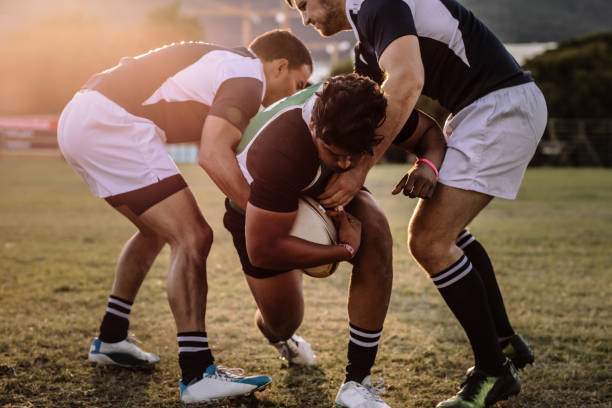 Rugby players striving to get to the ball Professional rugby player is blocked by the opposite team player on ground. Rugby players striving to get to the ball during the match. rugby stock pictures, royalty-free photos & images