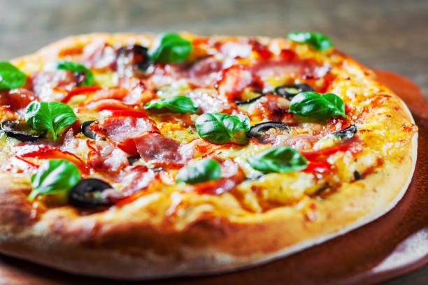 istock Pizza with Mozzarella cheese, ham, pepper, olive, meat, Tomato sauce, Spices and Fresh Basil. Italian pizza on wooden background 1095018022