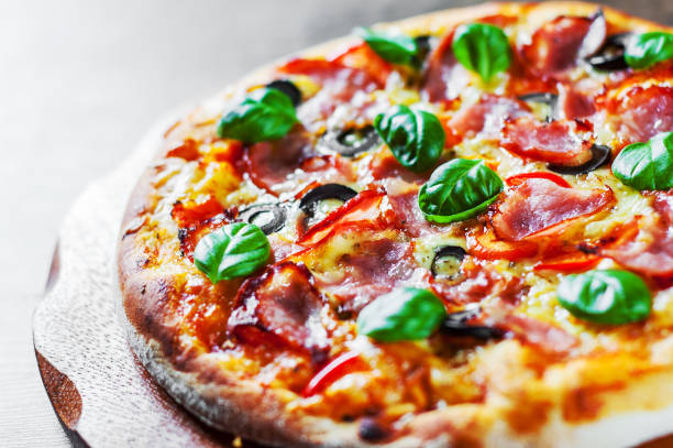 istock Pizza with Mozzarella cheese, ham, pepper, olive, meat, Tomato sauce, Spices and Fresh Basil. Italian pizza on wooden background 1095018024