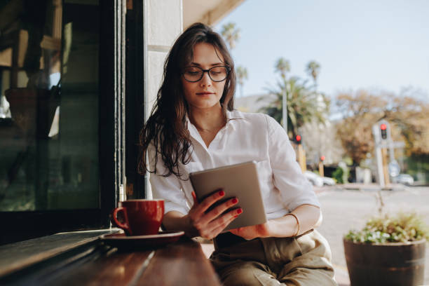 디지털 태블릿에 노력 하는 카페에 앉아 여자 - digital tablet women coffee shop coffee 뉴스 사진 이미지