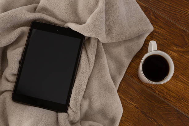 istock Digital tablet with blanket and black coffee on wooden background 1095022558