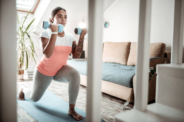 istock Attentive dark-haired woman doing squats with weightings 1095030110
