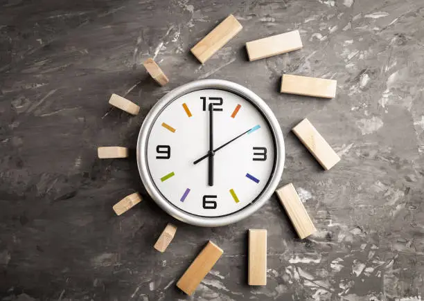 Time management concept. Big clock and wooden cubes, time comes to an end