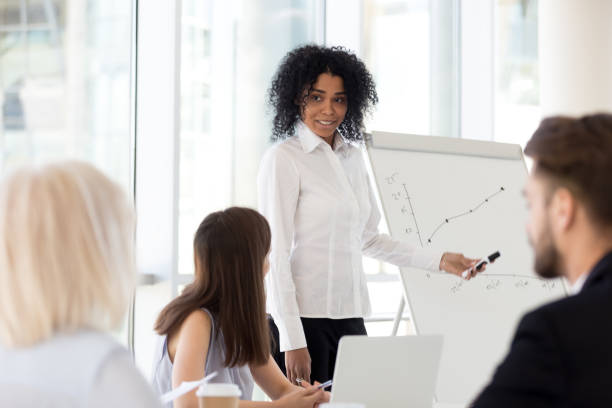 istock Smiling mixed-race mentor gives presentation at diverse team office training 1095046976