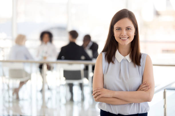 Millennial female team leader posing in modern office, portrait Millennial ambitious team leader, young employee, hr manager, female worker, intern girl smiling looking at camera, happy successful professional or business coach posing in modern office, portrait reduction looking at camera finance business stock pictures, royalty-free photos & images