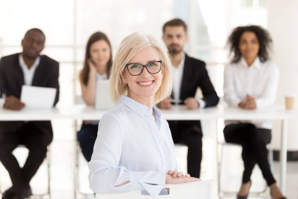 smiling senior woman job applicant looking at camera during interview - human resources job search skill teaching imagens e fotografias de stock