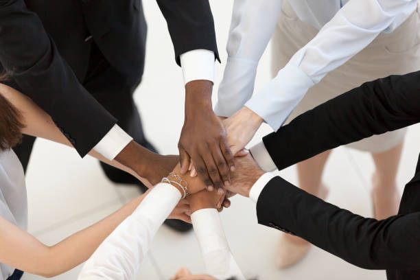 Diverse business people put hands together in pile, top view