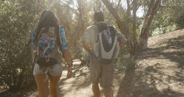 istock Backpacker couple hiking through forest trail with light shining through trees 1095055458