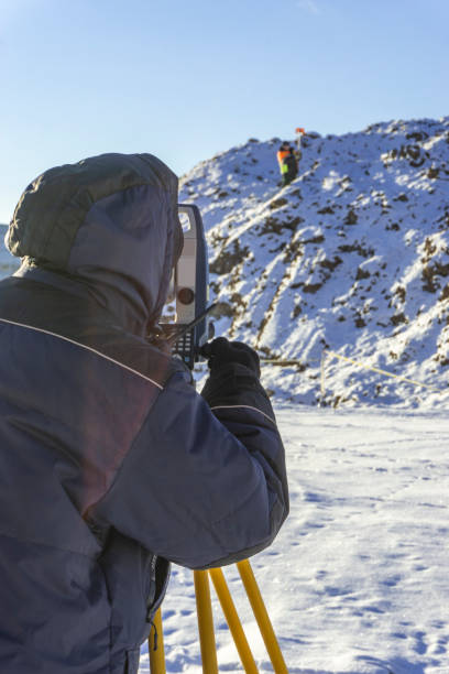 istock Surveyor and assistant conduct a topographical survey in the winter for cadastral work 1095058590