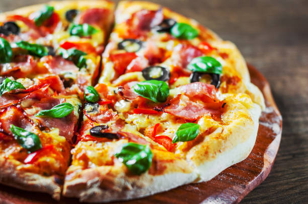 istock Pizza with Mozzarella cheese, ham, pepper, olive, meat, Tomato sauce, Spices and Fresh Basil. Italian pizza on wooden background 1095059148