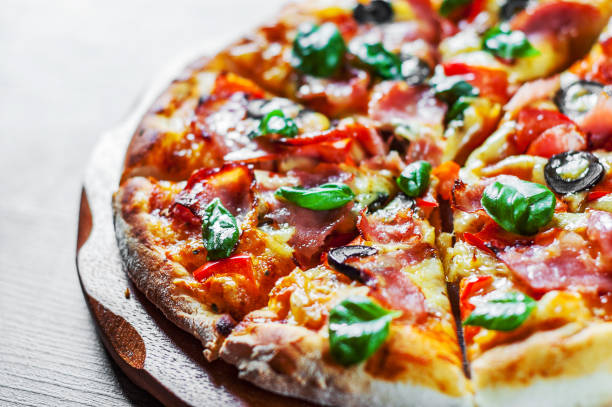 istock Pizza with Mozzarella cheese, ham, pepper, olive, meat, Tomato sauce, Spices and Fresh Basil. Italian pizza on wooden background 1095059150
