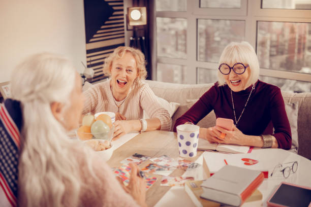 Delighted aged woman looking at her smartphone