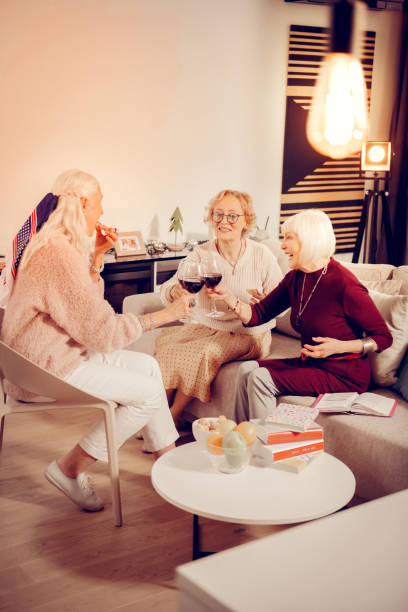 Joyful aged women drinking red wine together