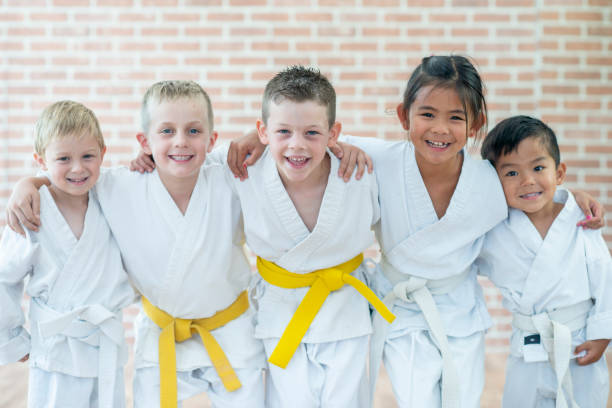 Martial Arts Kids Five kids are posing together and embracing while attending their martial arts class. karate stock pictures, royalty-free photos & images