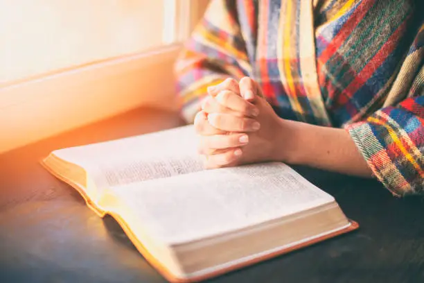 Photo of Woman with praying over her opened bible in the sunlight