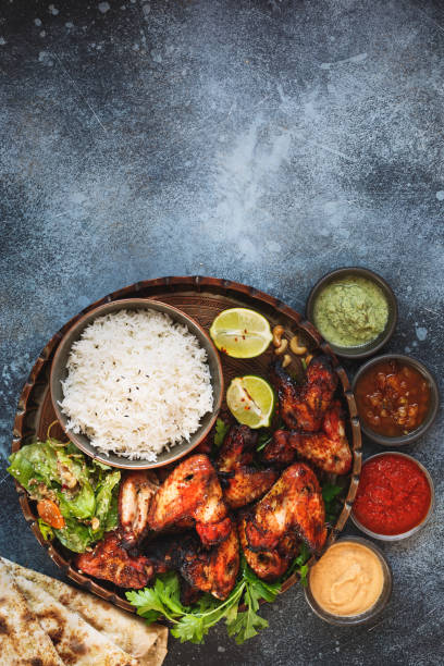 pollo de tandoori ahumado, asado servidas con arroz pilau, naan de ajo suave queso con salsas que sumergen chutney diferentes alas - wing spicy chicken wings chicken sauces fotografías e imágenes de stock