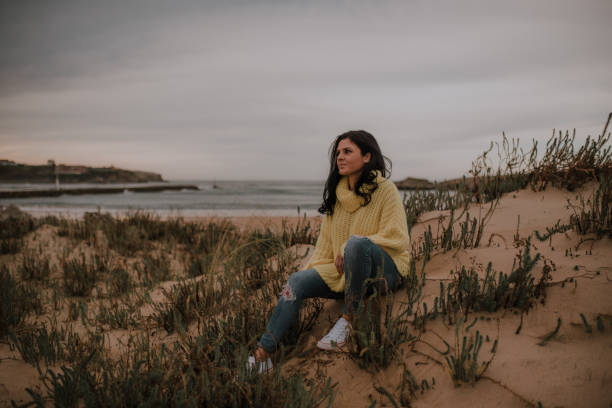 istock Woman sitting by a beach 1095080372