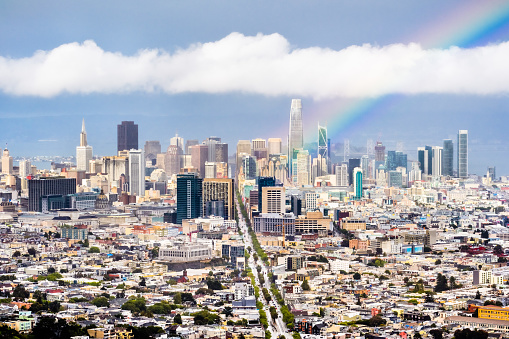 Aerial view of San Francisco's financial district skyline on a rainy day, bright rainbow rising from downtown;
