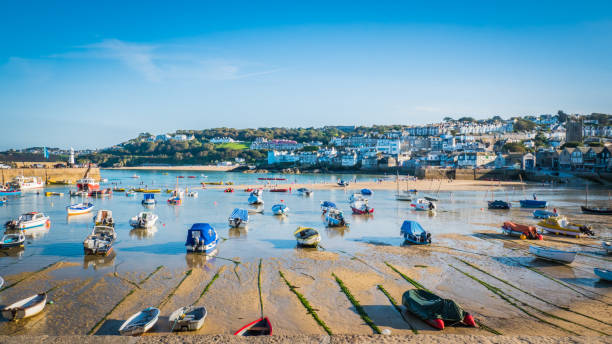 St. Ives bay at sunset in Cornwall, UK Fishing boats during low tide in the evening at sunset at the harbor of St Ives vacation, fishing town in St. Ives, Cornwall, United Kingdom, UK. fish village stock pictures, royalty-free photos & images