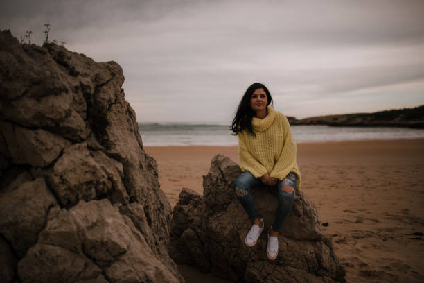 istock Young woman sitting on rocks 1095095536