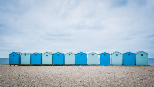 Charmouth beach houses in the UK Blue beach holiday house by the English Channel on Jurassic coast in Charmouth, Dorset, United Kingdom, UK. British summer holidays, hilly countryside, beach summer destination. christchurch england photos stock pictures, royalty-free photos & images