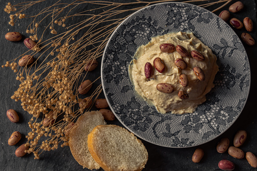 Hummus of Pinto beans with bread to spread. Beautiful presentation of a delicious dish made with legumes. Background of a nutritive food.