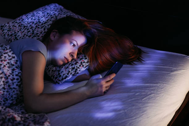 istock Young woman using smartphone in bed at night 1095120868