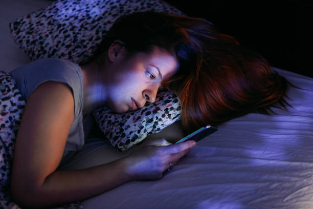 istock Young woman using smartphone in bed at night 1095120870