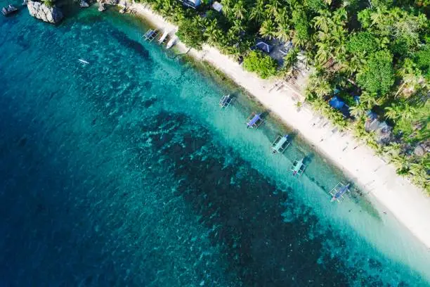 An idyllic tropical scene of sand, sun, boats, and water on the beautiful island of Guimaras, Western Visayas, Philippines.