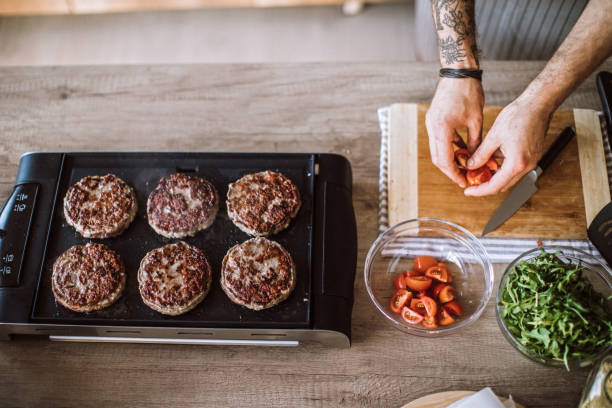 istock Chef Making Fresh Ripe Tomato Salad While Baking Homemade Hamburgers 1095131344