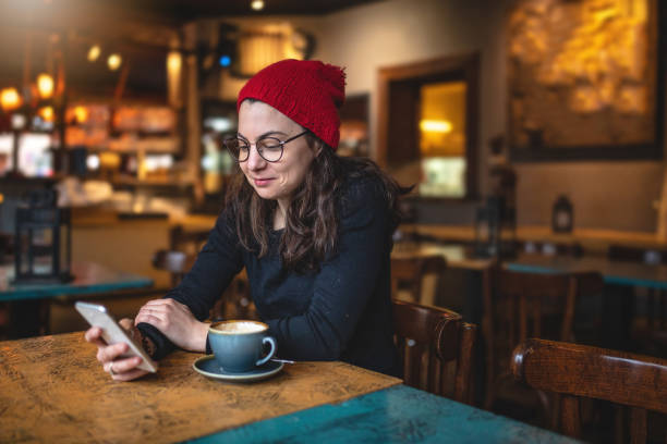 istock Cheerful girl texting while drinking coffee at a cafe 1095143560