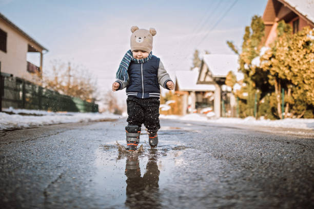 Baby boy running happily through puddles