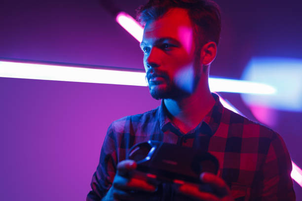 istock Young man holding VR glasses in neon 1095150220