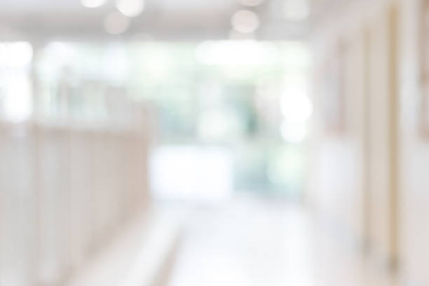 Corridor in school or office building blur background with blurry interior view empty hall way, glass curtain wall and floor with exterior light illumination