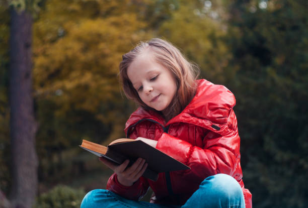istock Girl Reading Book While Sitting In Park 1095168644