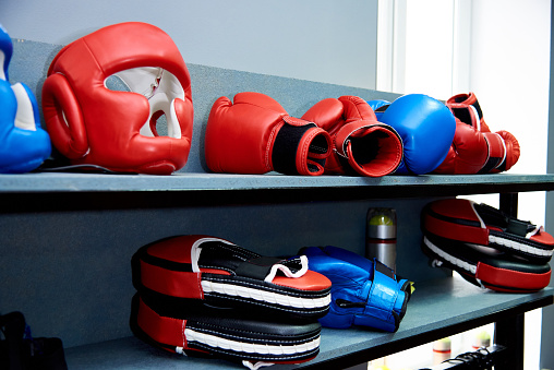 Sports equipment for hand-to-hand combat. A protective helmet, gloves and Boxing paws lie on a shelf.