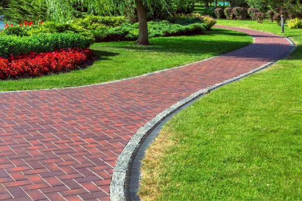 Red blocks footpath with drainage system in a park with green lawns and landscape design with bushes and red flowers. Red blocks footpath with drainage system in a park with green lawns and landscape design with bushes and red flowers. pedestrian walkway stock pictures, royalty-free photos & images