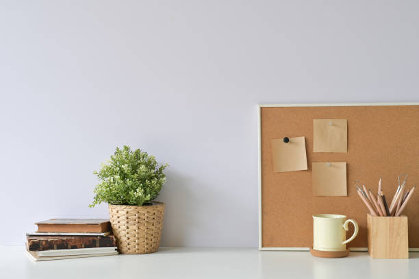 istock Workspace with books, coffee, pencil, plant and sticky note paper on board with office white desk. 1095178956