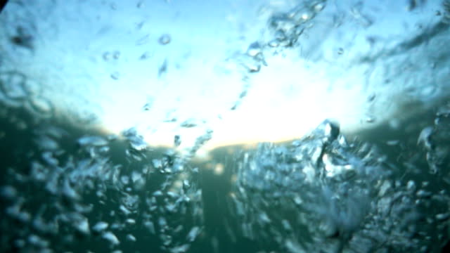 Diving into the water. Falling into the water in slow motion. Different-sized bubbles in foaming turquoise water. Sinking. Version1.