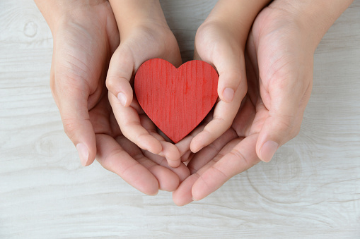 Heart object covered by mother and child's hands