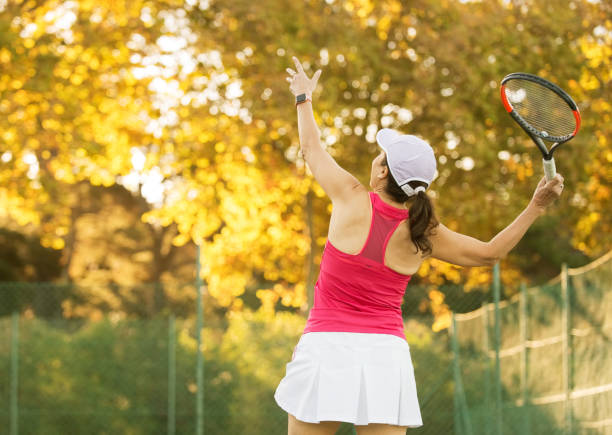 mujer madura que sirve una pelota de tenis. - tennis serving female playing fotografías e imágenes de stock