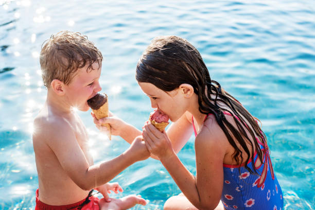 istock Child sharing an ice cream by the pool 1095193740