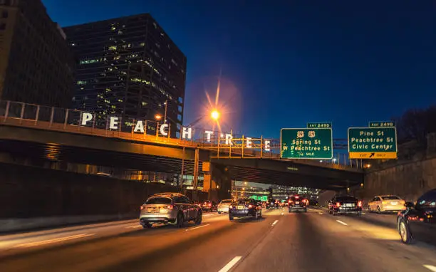 The lit Peachtree sign on the bridge identifying Peachtree Street from afar.
