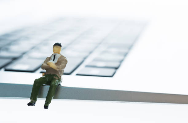 бизнесмен фигурка сидит на клавиатуре - figurine small plastic businessman стоковые фото и изображения