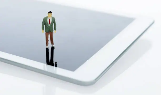Photo of Businessman figurine standing on digital tablet