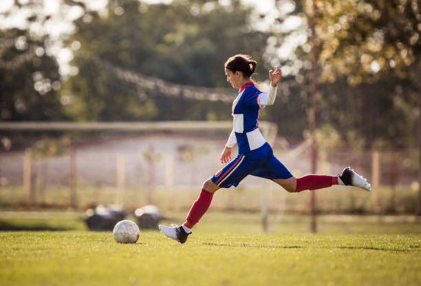 Teenage soccer player about to kick the ball during the match. Teenage girl running with soccer ball on a playing field and about to kick the ball. offense sporting position stock pictures, royalty-free photos & images