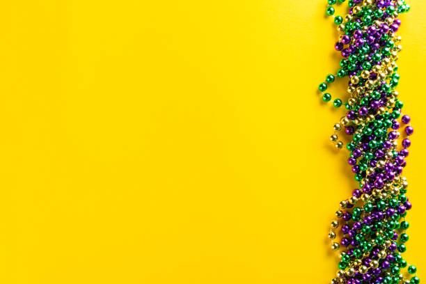 Mardi gras carnival concept - beads on yellow background Mardi gras carnival concept - beads on yellow background, top view bead photos stock pictures, royalty-free photos & images
