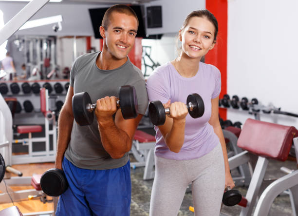 istock Sporty guy and girl posing with dumbbells 1095278332